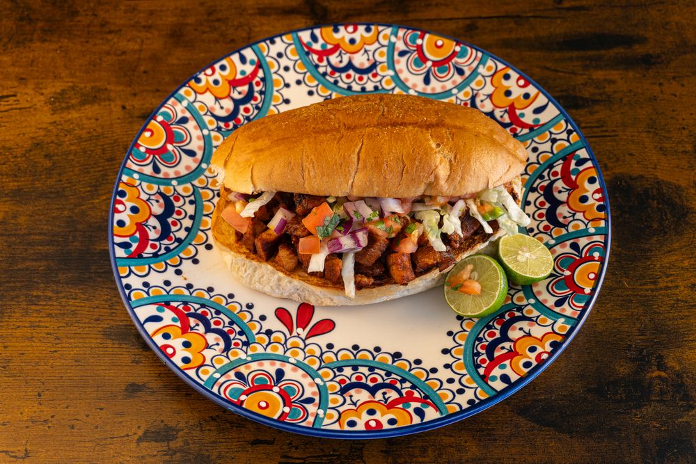 Mexican restaurant entrees served on colorful patterned plates with traditional garnishes.