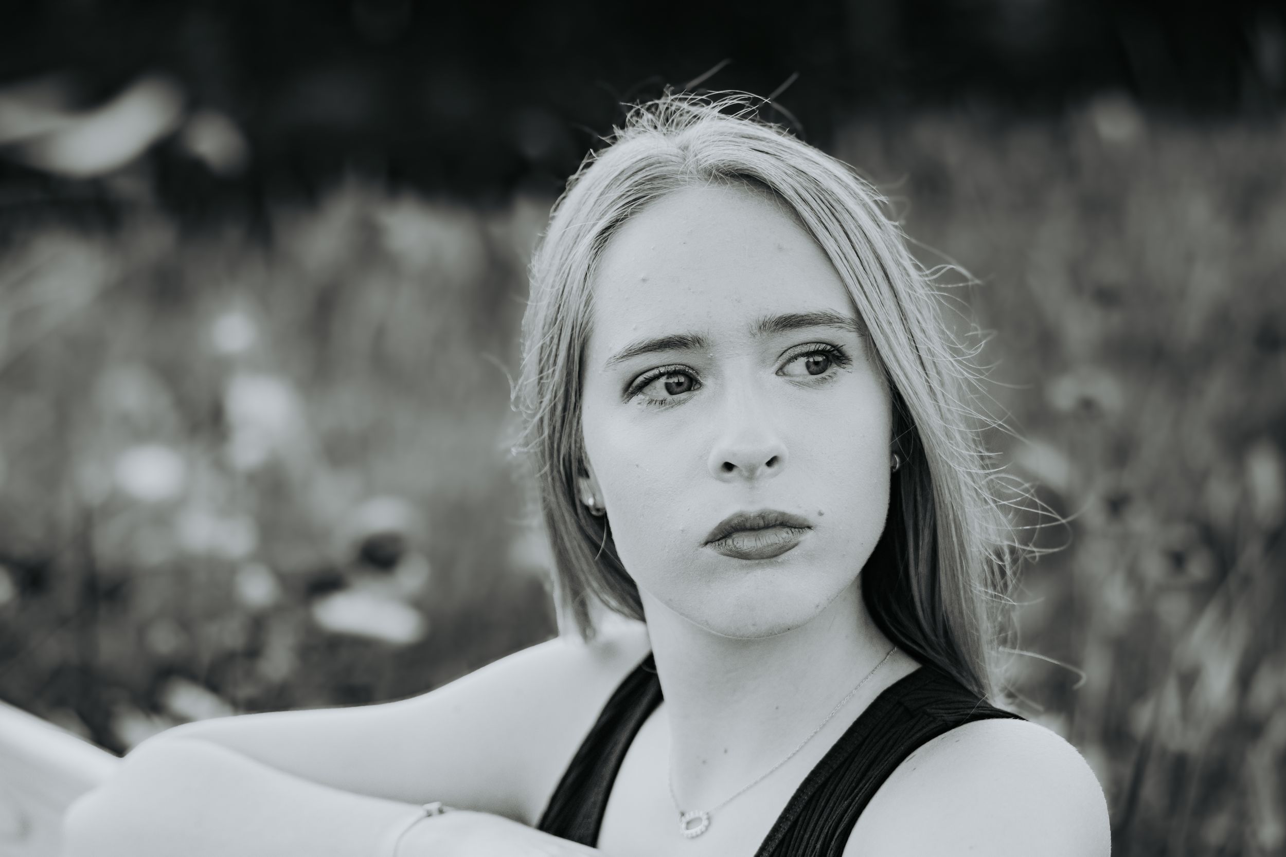 A close-up black and white photo series showing different angles of someone in a black top against a dark background.