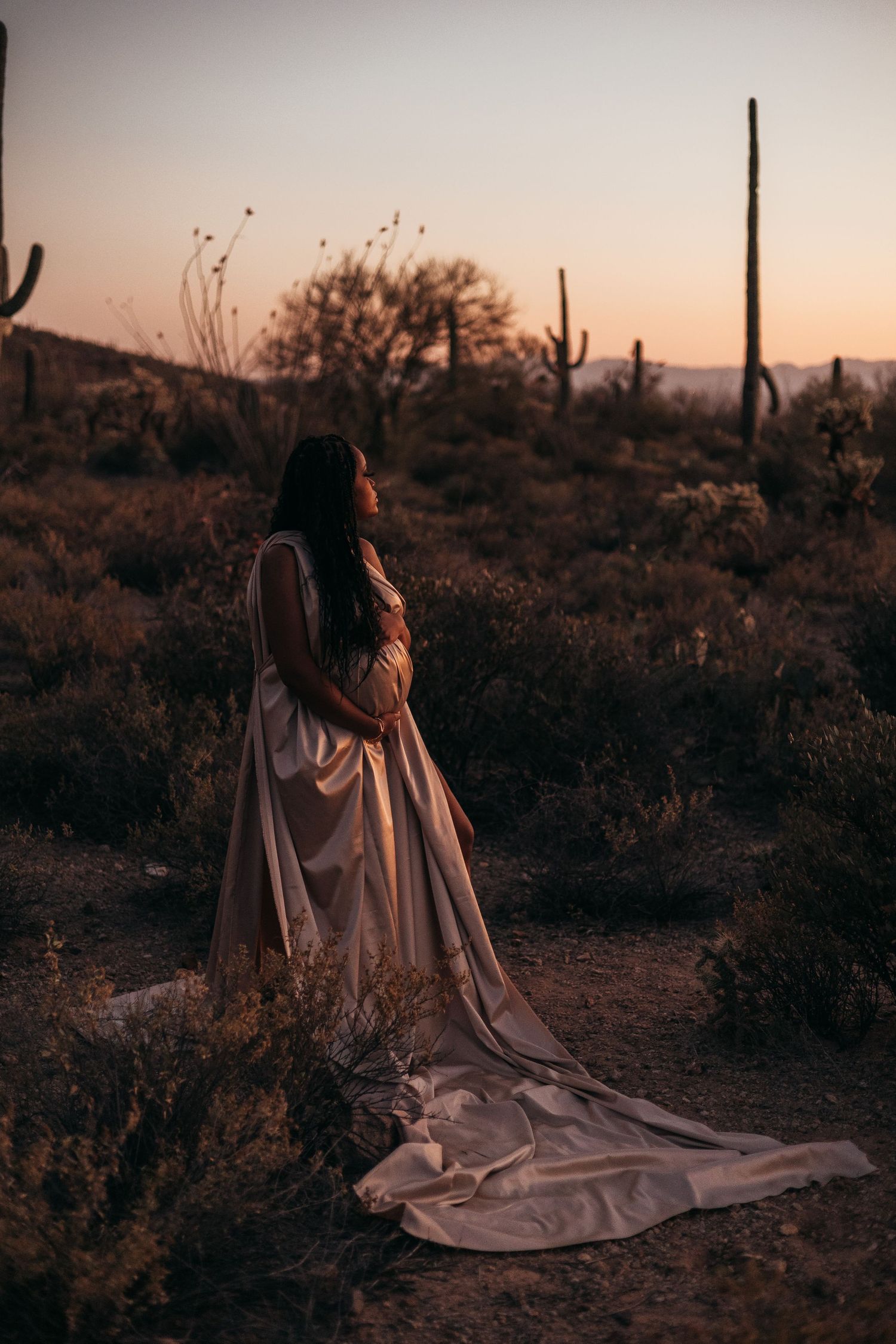 Ethereal desert photoshoot featuring flowing dress against sunset backdrop with saguaro cacti.