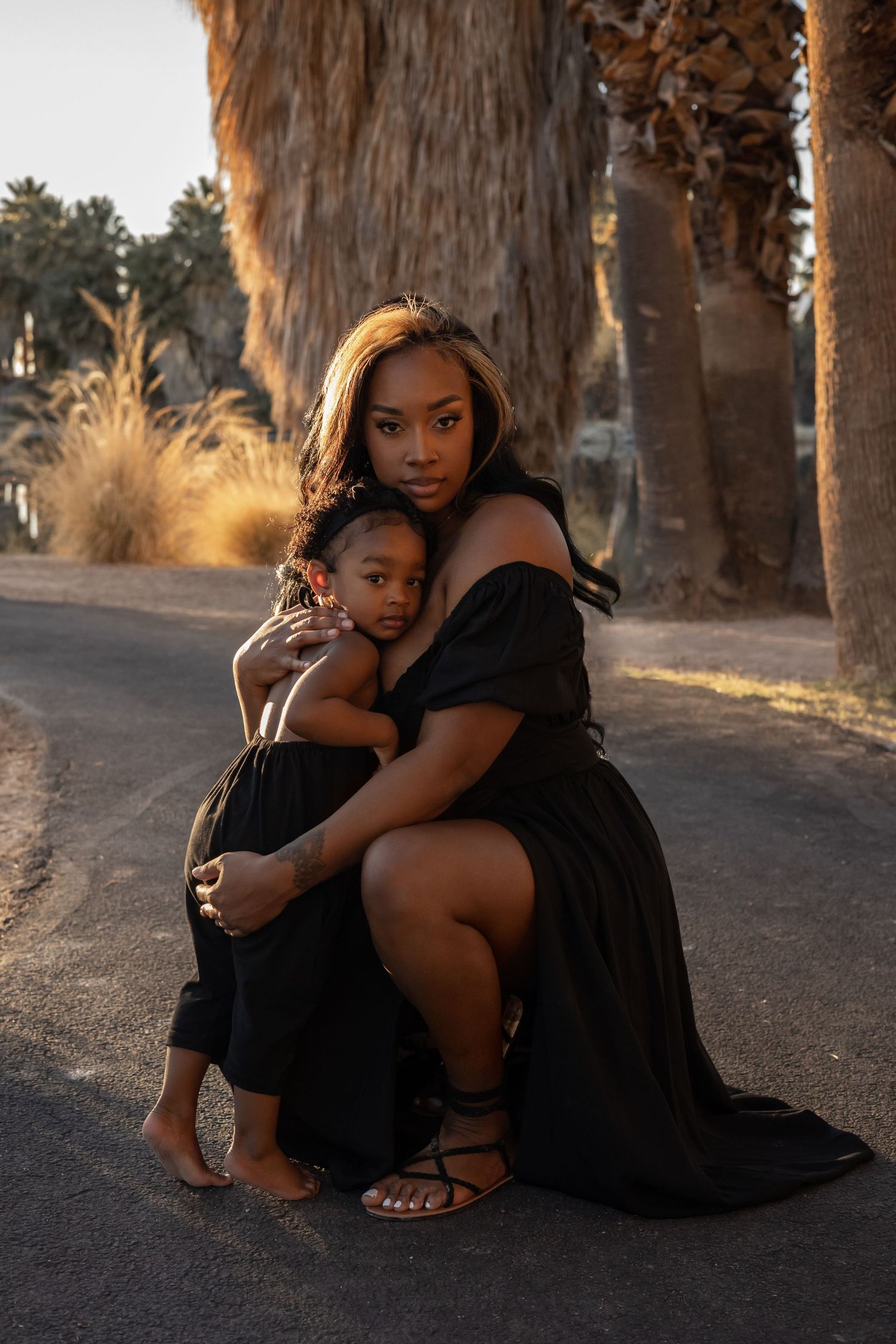 A tender moment between parent and child captured at sunset against a backdrop of palm trees.