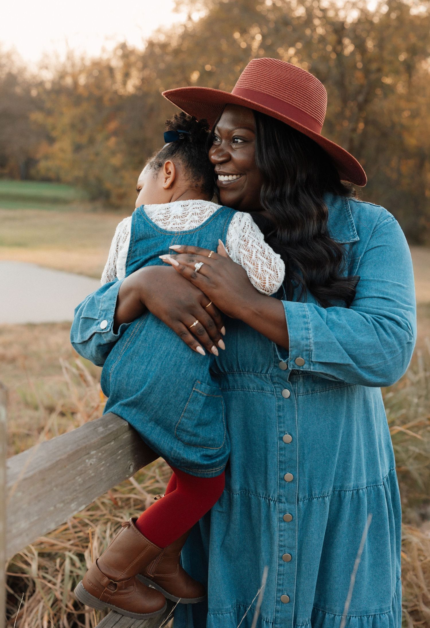 A couple in casual attire share tender embraces outdoors during golden hour in a field.