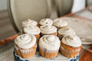 Homemade cupcakes topped with swirled vanilla buttercream frosting displayed on a blue and white plate.