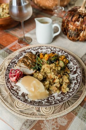 Traditional Thanksgiving dinner plate with stuffing, vegetables, and gravy served on an ornate brown and white patterned dish.