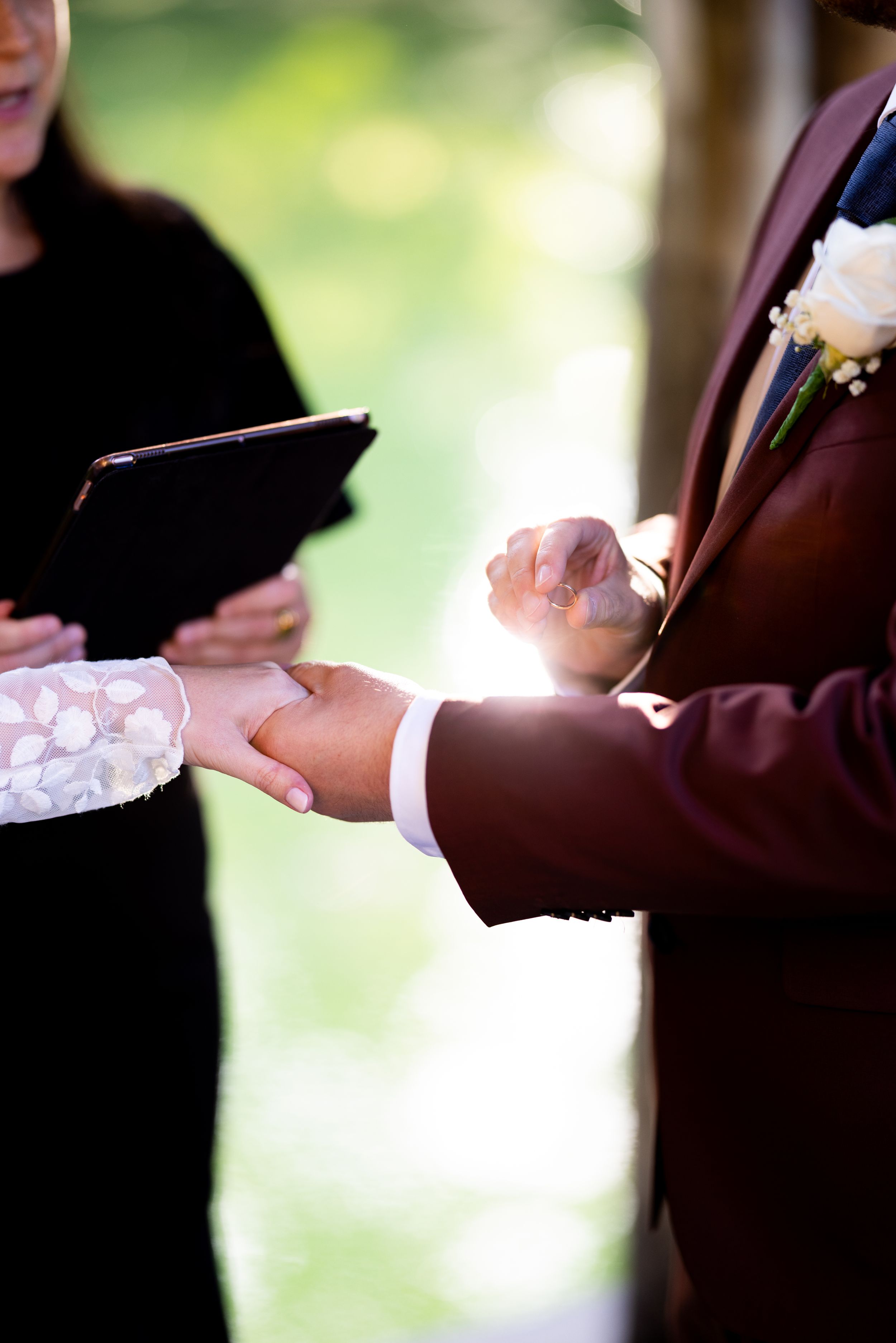 Close-up of wedding ceremony ring exchange with sunlight streaming through.