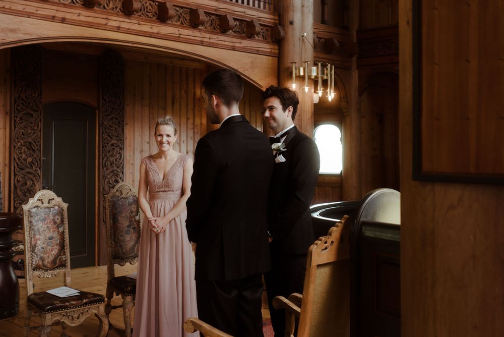 A wedding ceremony in progress inside an ornate historic venue with dramatic lighting.
