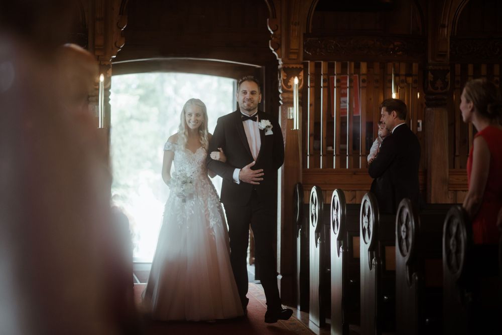 A wedding processional captured in a beautifully lit church aisle.