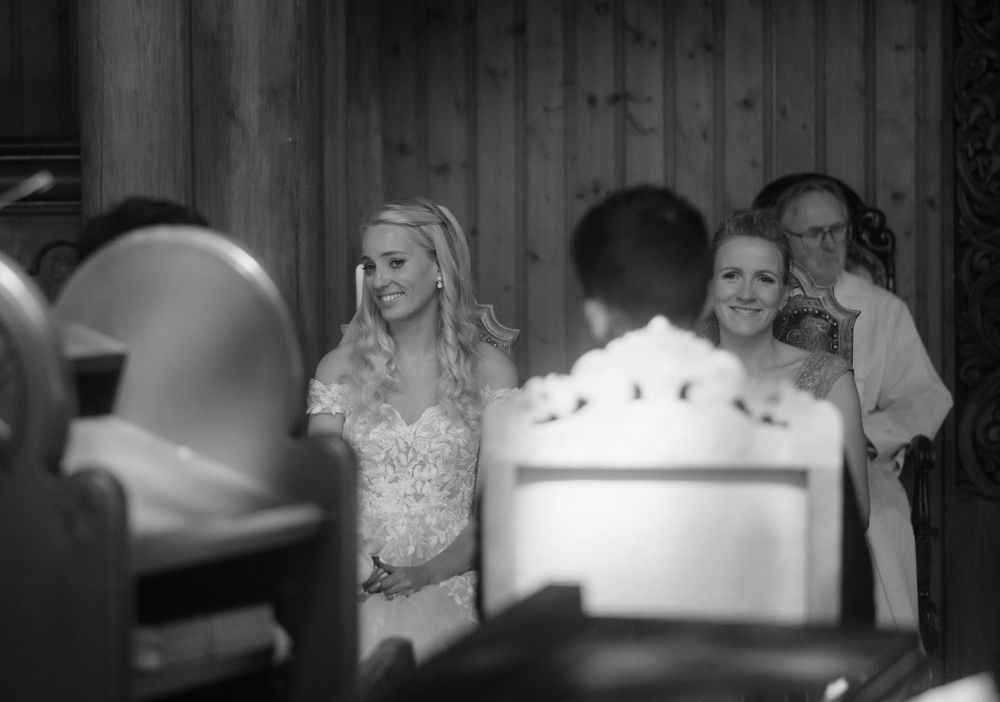 Black and white candid shot of wedding guests during a church ceremony.