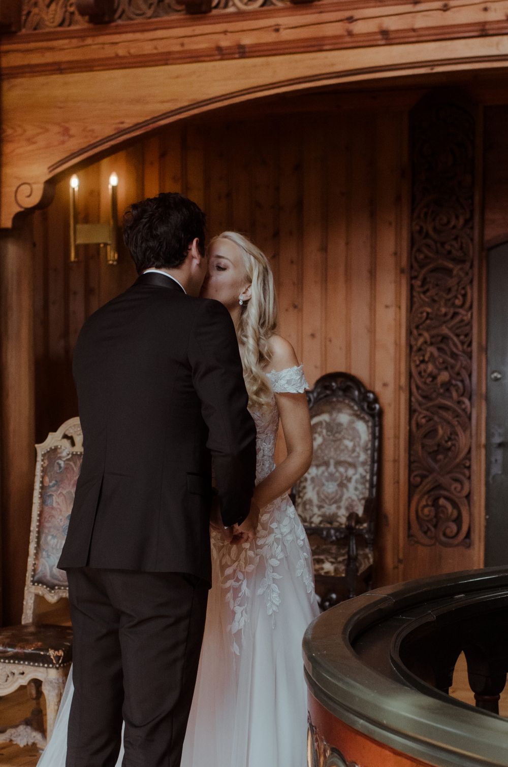 Romantic wedding moment in an ornate wooden room with candlelight and vintage decor.