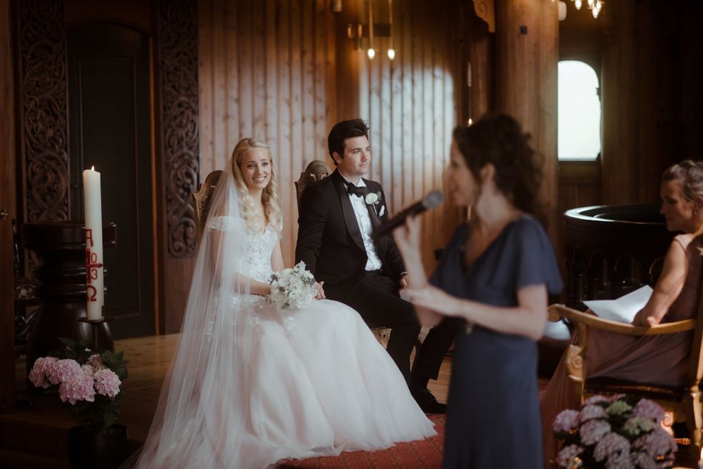 Intimate wedding ceremony taking place in an elegant wood-paneled room with floral decorations.