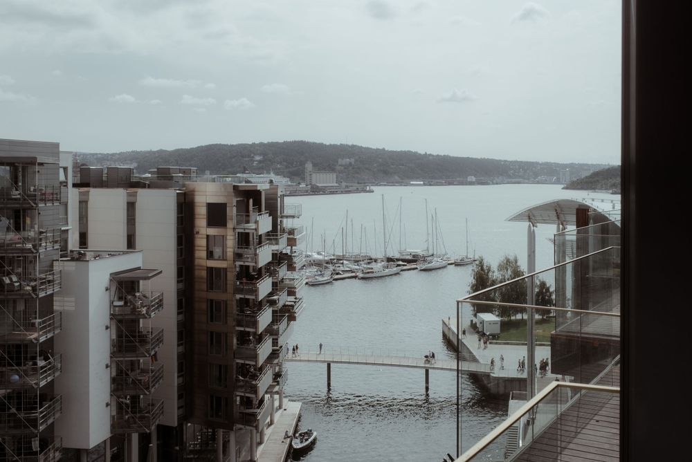 Moody cityscape view of a marina with boats and modern apartment buildings on an overcast day.