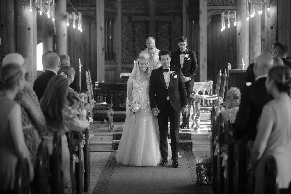 A black and white photo of a wedding ceremony in a church with guests lining the aisle.