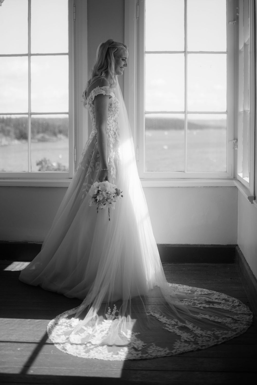 Black and white photo of wedding dress silhouetted against bright windows.