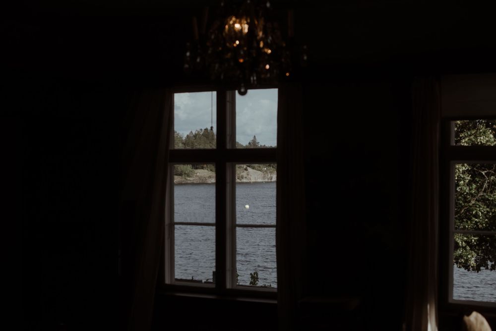A dark window frame silhouetted against a lake view with pendant lighting.