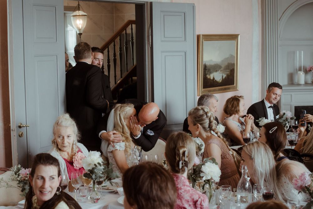 Guests seated at an elegant reception dinner with floral centerpieces and formal table settings.
