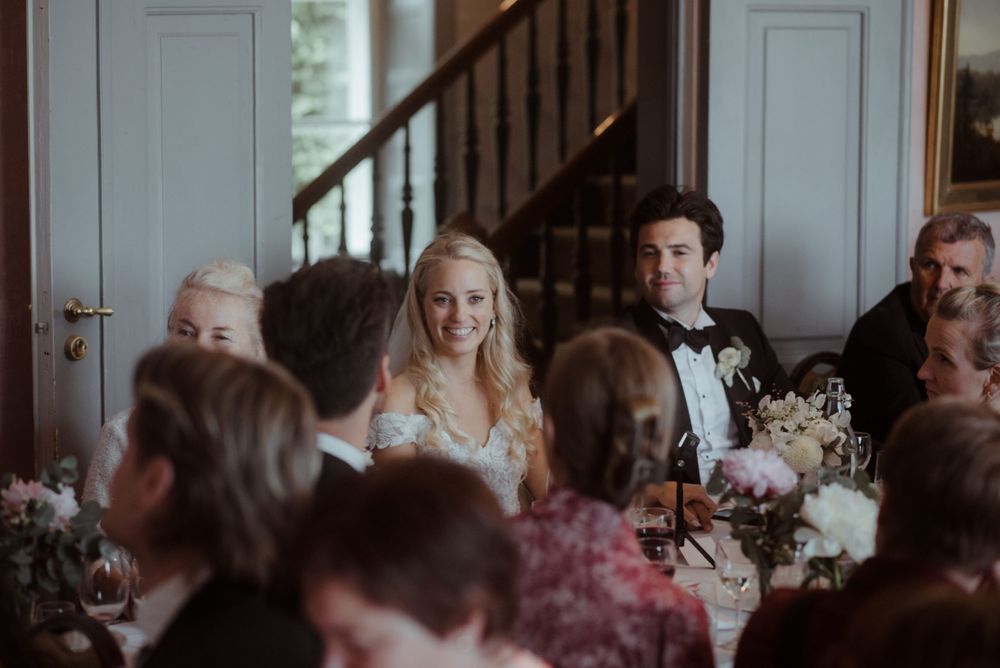 Wedding reception dinner in an elegant room with paneled walls and formal table settings.