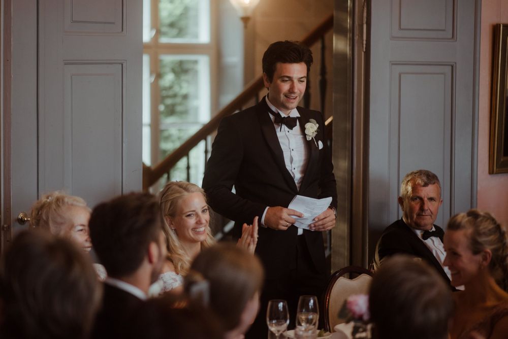 Formal dinner speech at wedding reception with traditional interior and candlelit atmosphere.