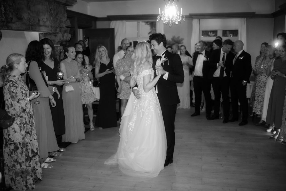 A couple shares their first dance surrounded by guests at an elegant wedding reception.