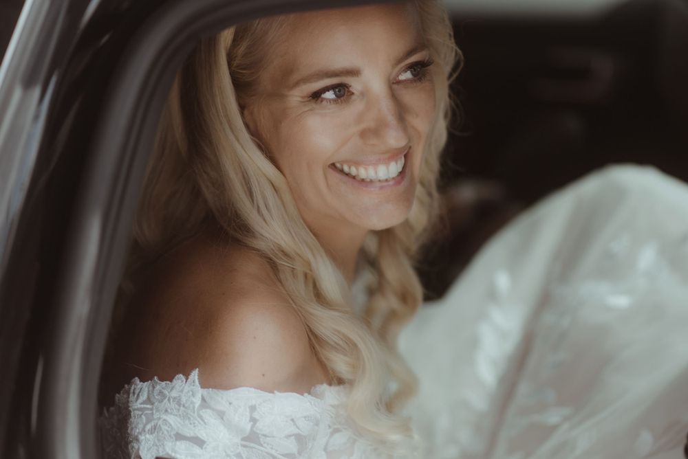 A joyful moment captured through a car window on a wedding day.