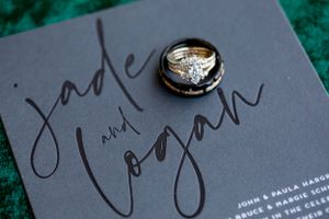 Wedding rings photographed on dark gray stationery with elegant calligraphy.