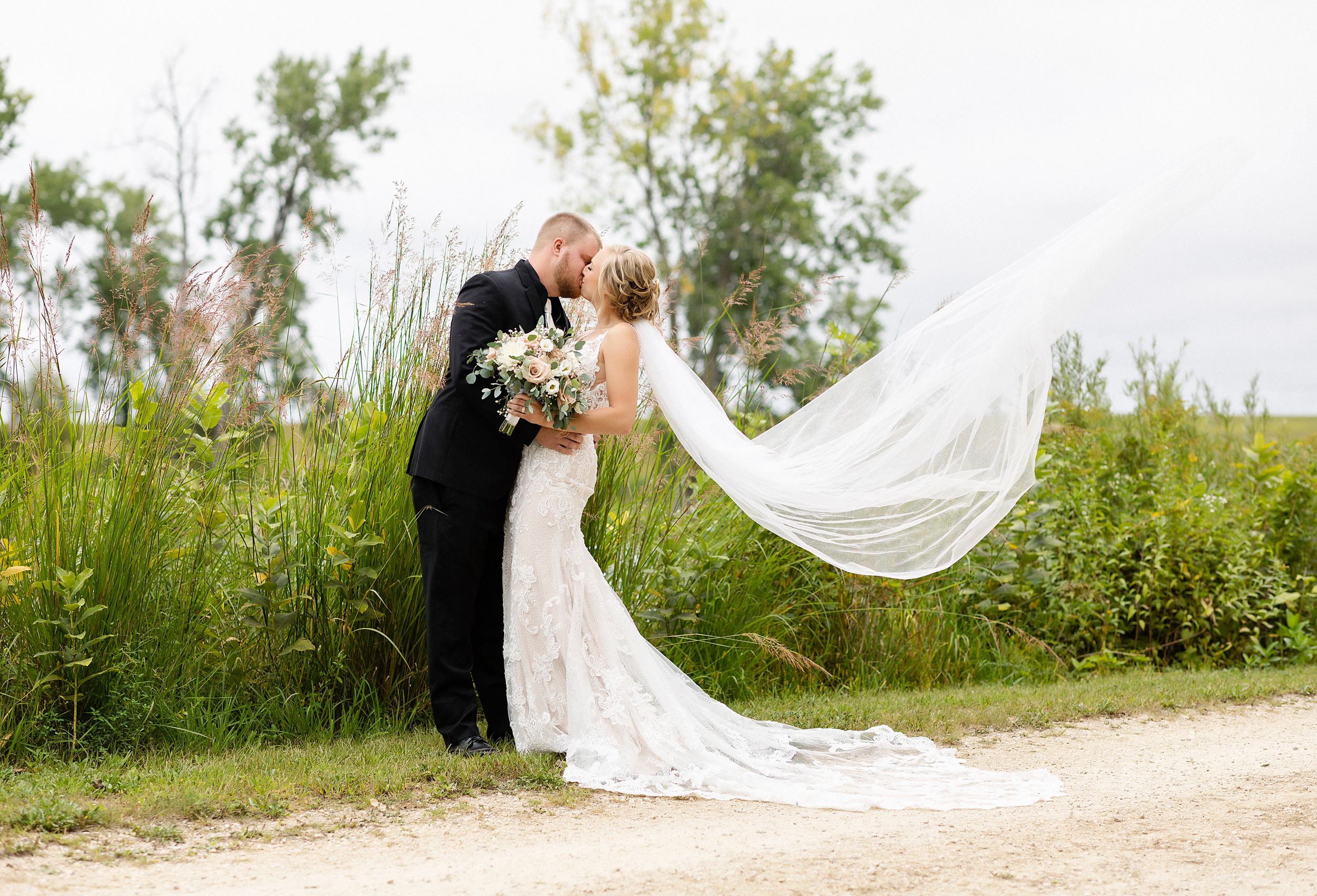 A romantic moment captured with a flowing veil against a natural landscape background.