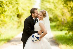 Classic wedding portrait on garden path with blue and white bouquet.