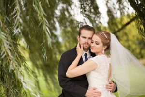 Romantic portrait under willow tree branches with soft natural lighting.