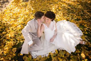 Autumn wedding portrait with couple on bed of golden leaves.