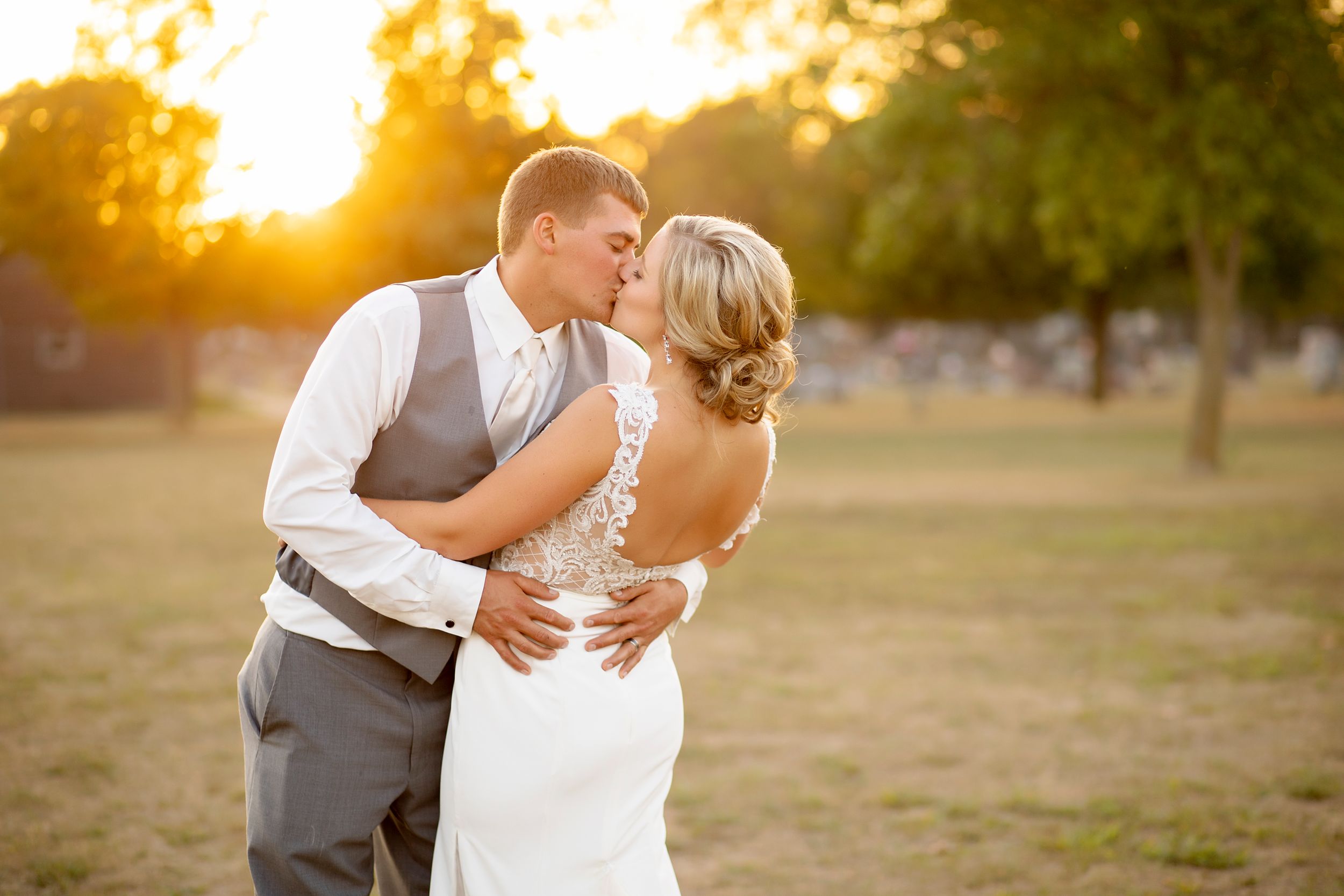 Romantic sunset wedding portrait in a field with couple embracing.