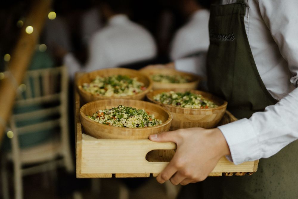 Appetizers are being served on wooden boards at an elegant catering event.