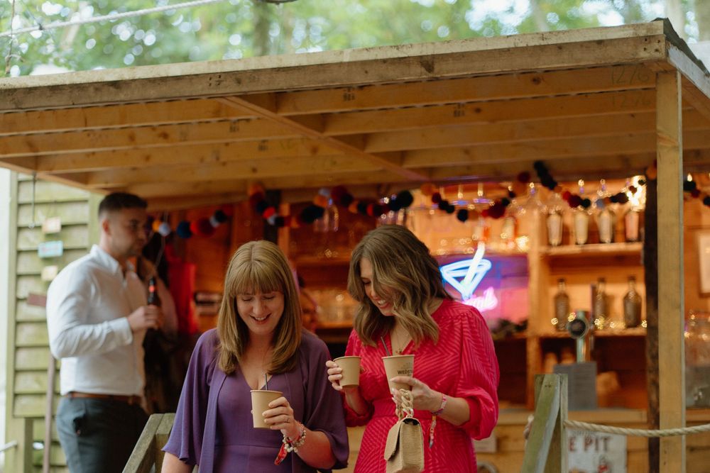 Warm string lights illuminate a rustic wooden bar setup at an outdoor event venue.