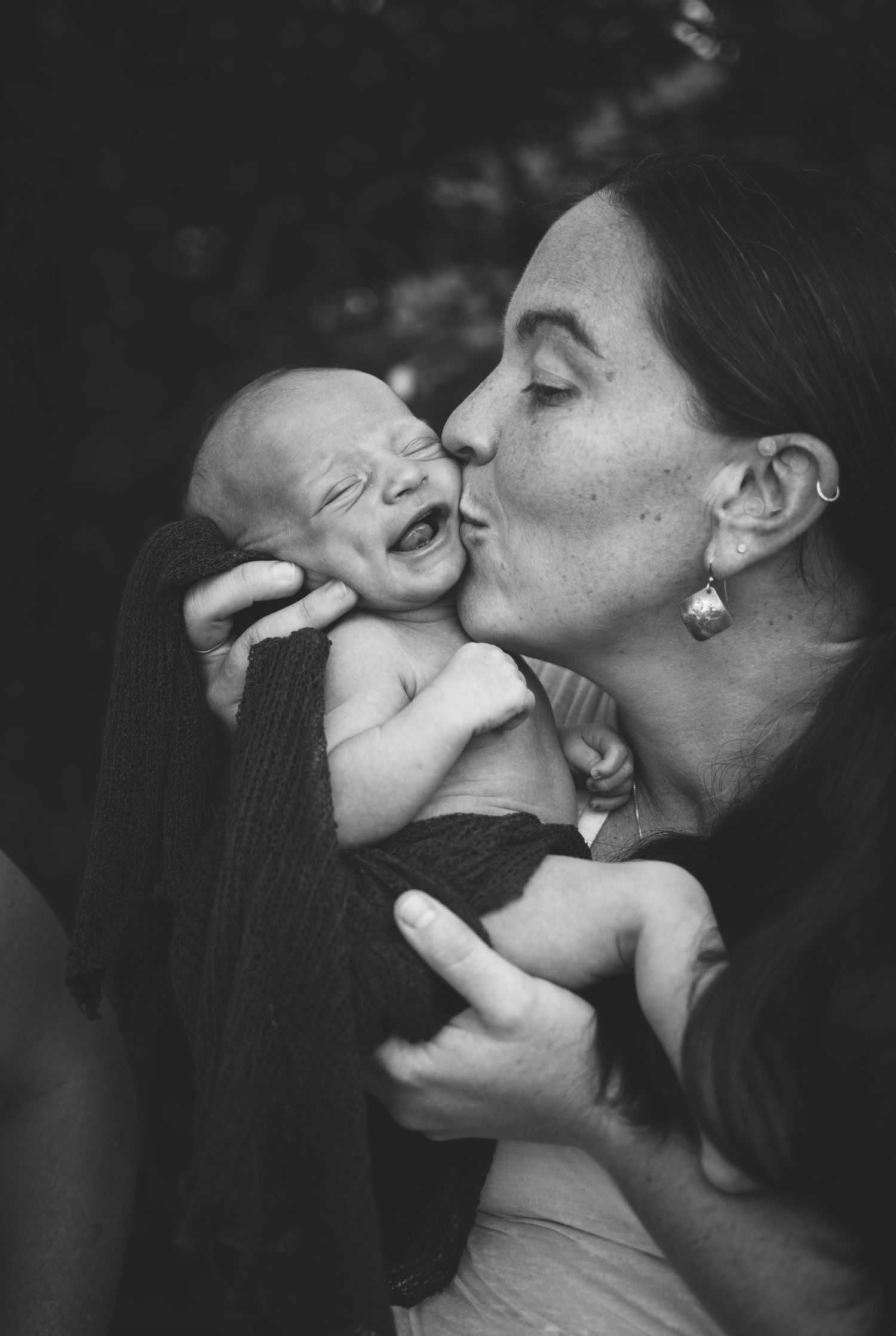 Black and white portrait of tender moment between parent and laughing baby.