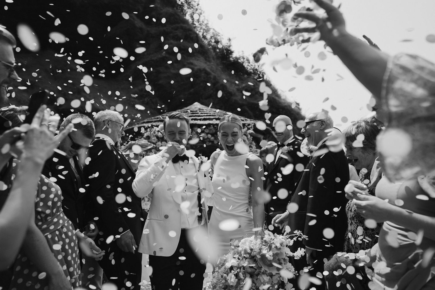 Bride and groom confetti throw at tunnels beach wedding venue in north Devon
