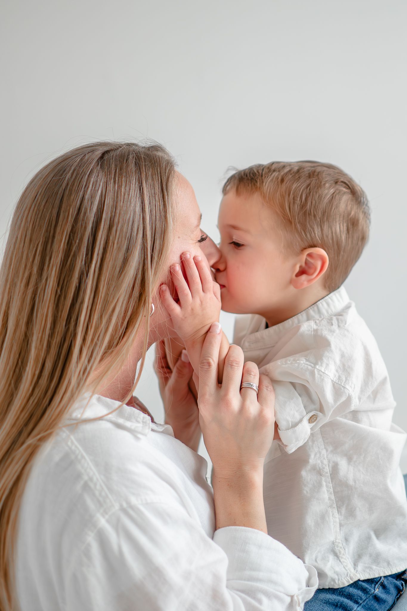 A tender moment shared between two people in white shirts as they gently touch faces together.