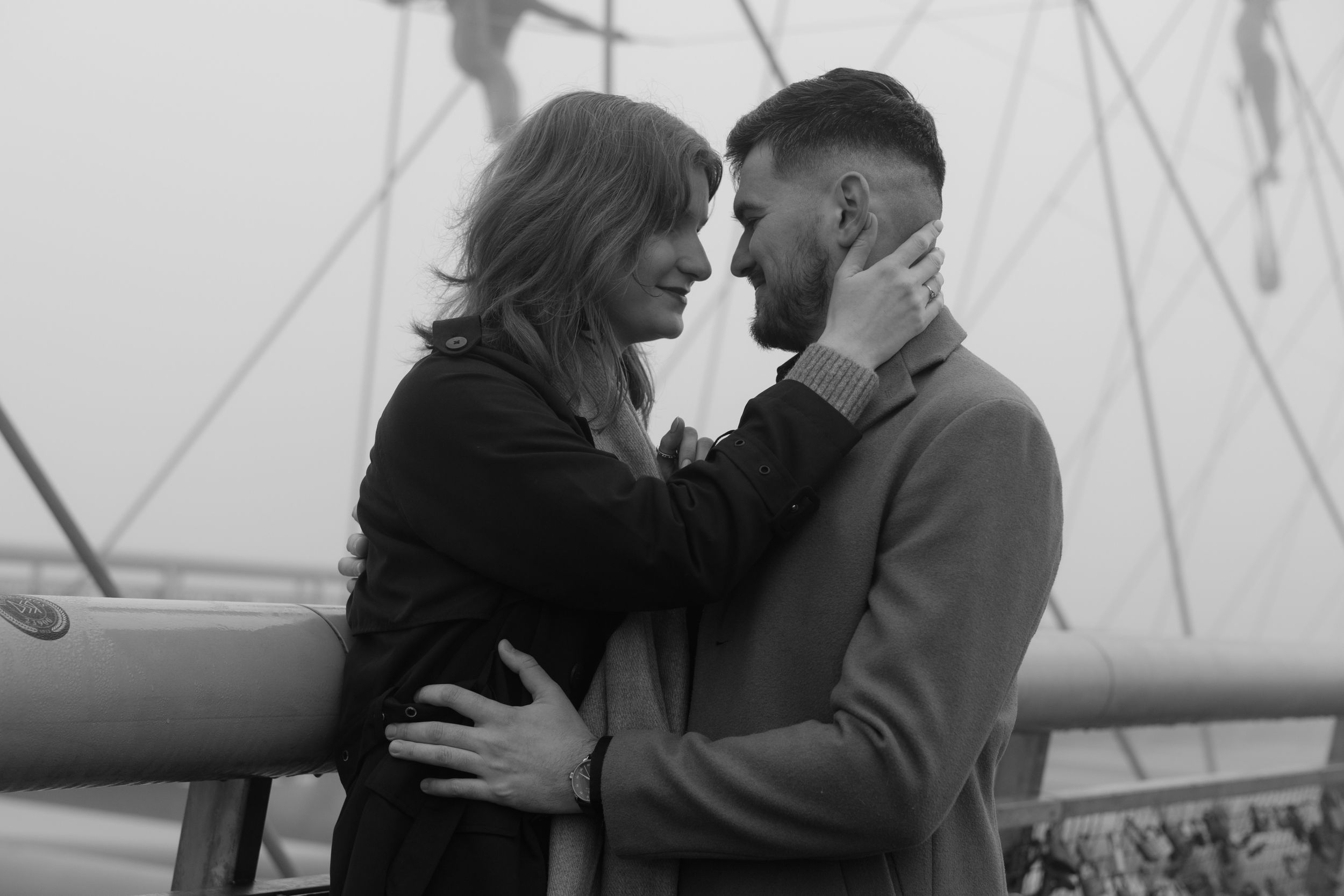 A romantic black and white portrait of a couple embracing intimately on a sailboat deck.