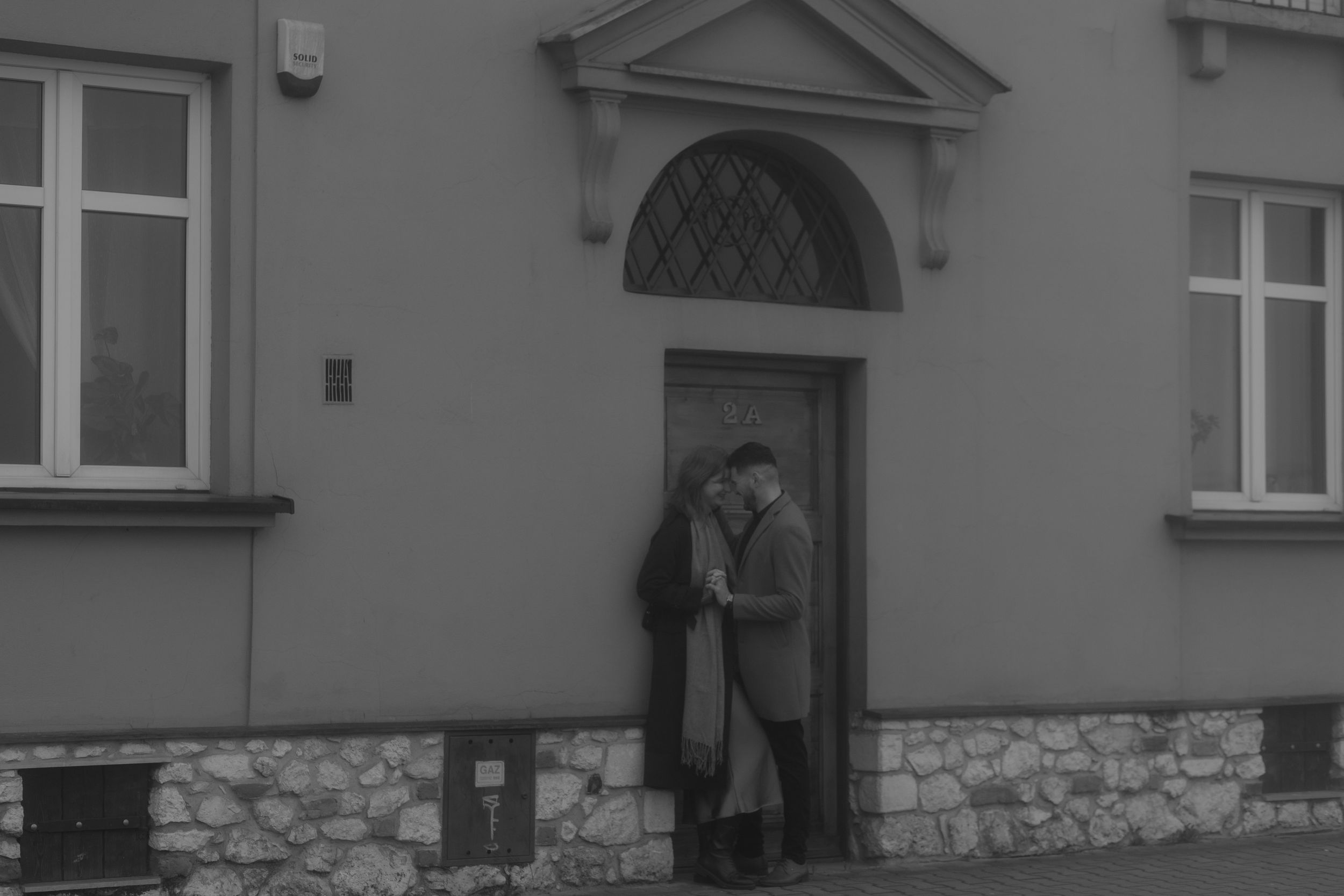 Vintage black and white photograph showing a figure standing in a doorway of a stone-based building.