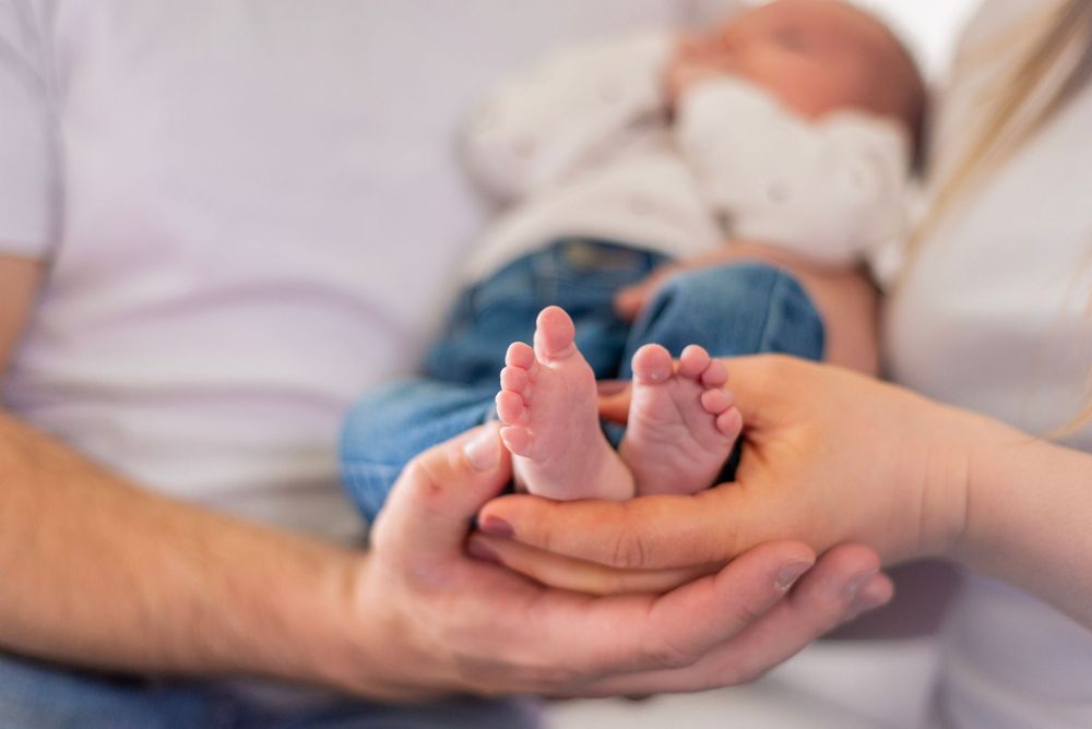 Tiny baby feet being gently cradled in adult hands showing a tender parenting moment.