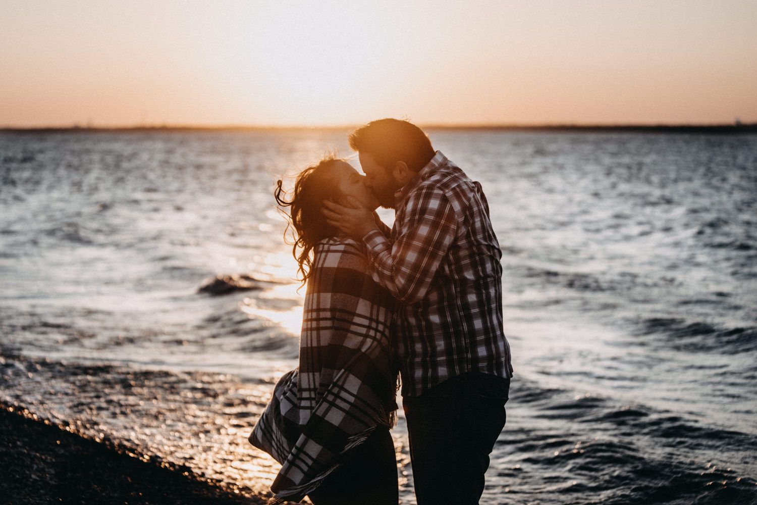 A romantic wedding couple embraces while dancing together outdoors against a cloudy sky in a candid moment.