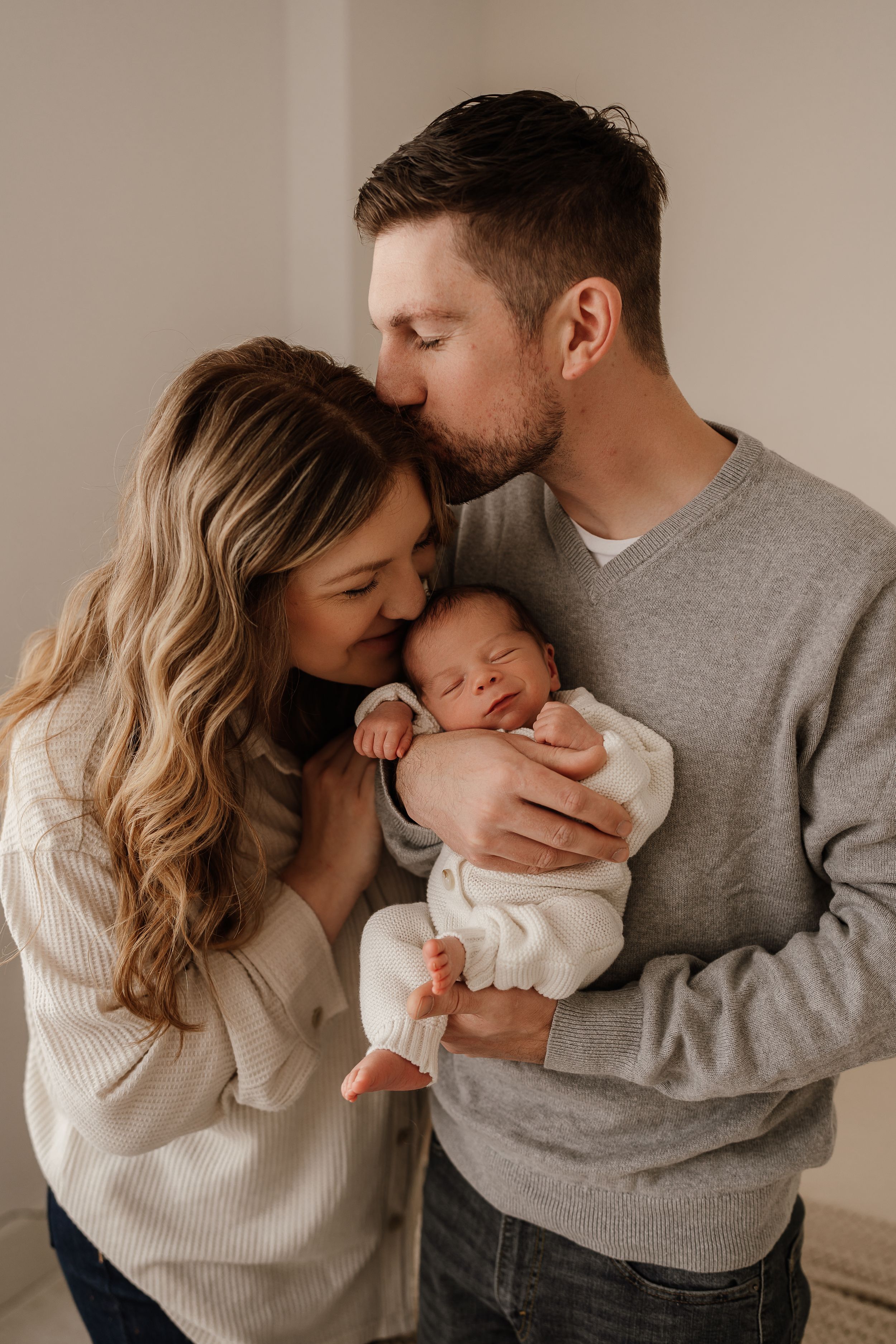Tender family moment with new parents cradling sleeping newborn.