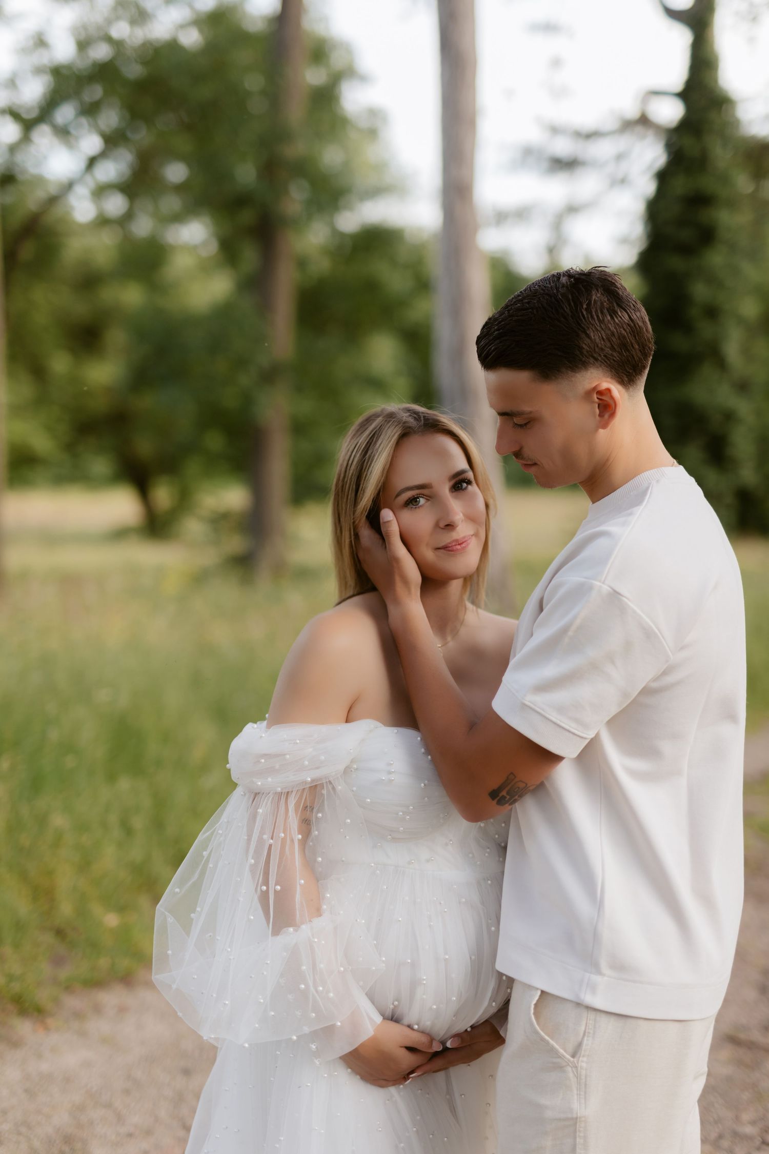 Romantic couple photos in white outfits against natural forest backdrop.