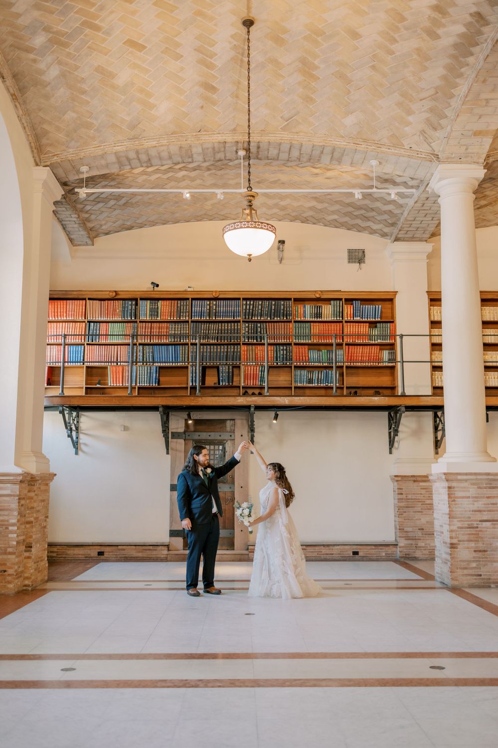 Classic library wedding portrait with towering bookshelves and architectural details.
