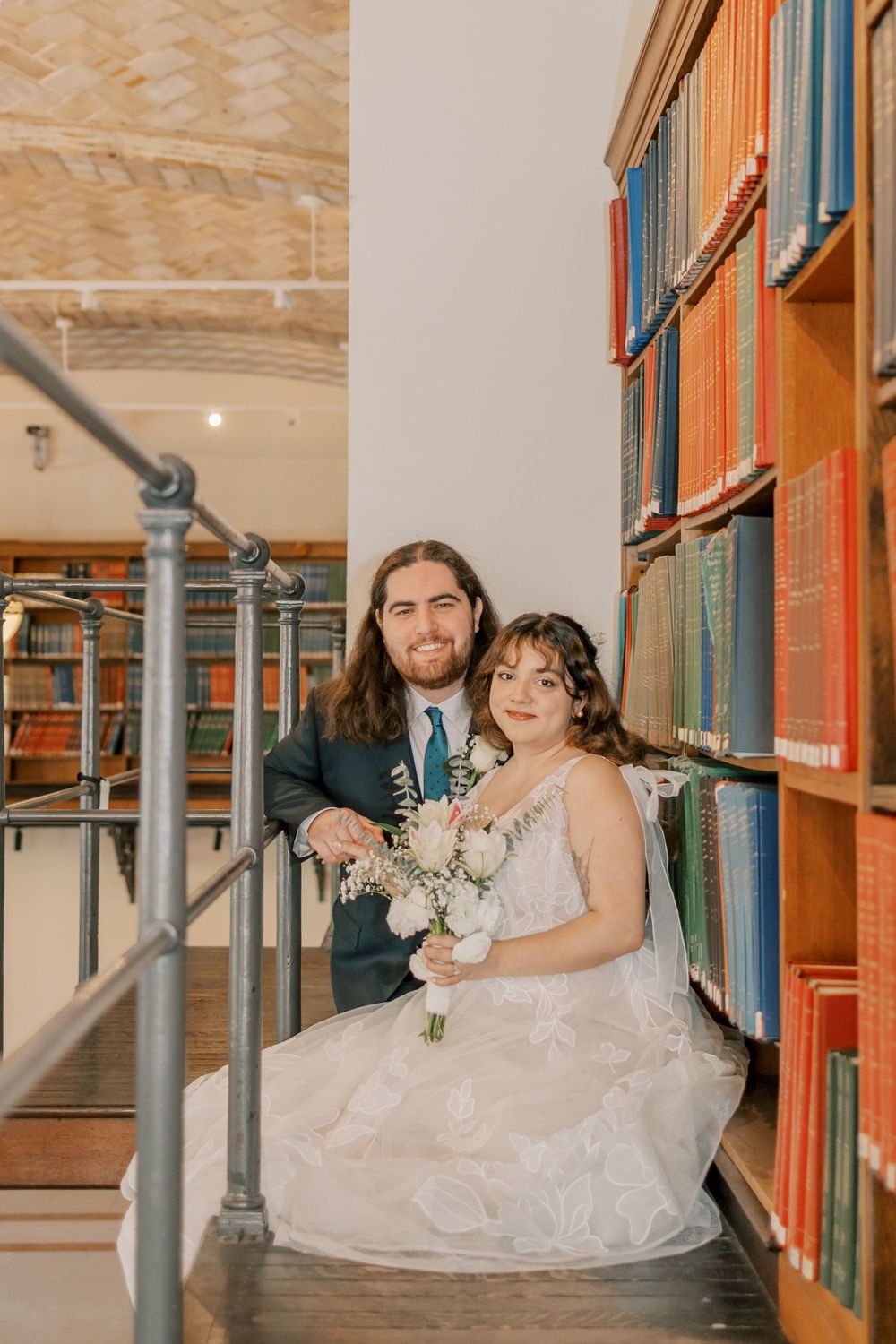 Intimate wedding portrait by vintage bookshelves in historic library setting.