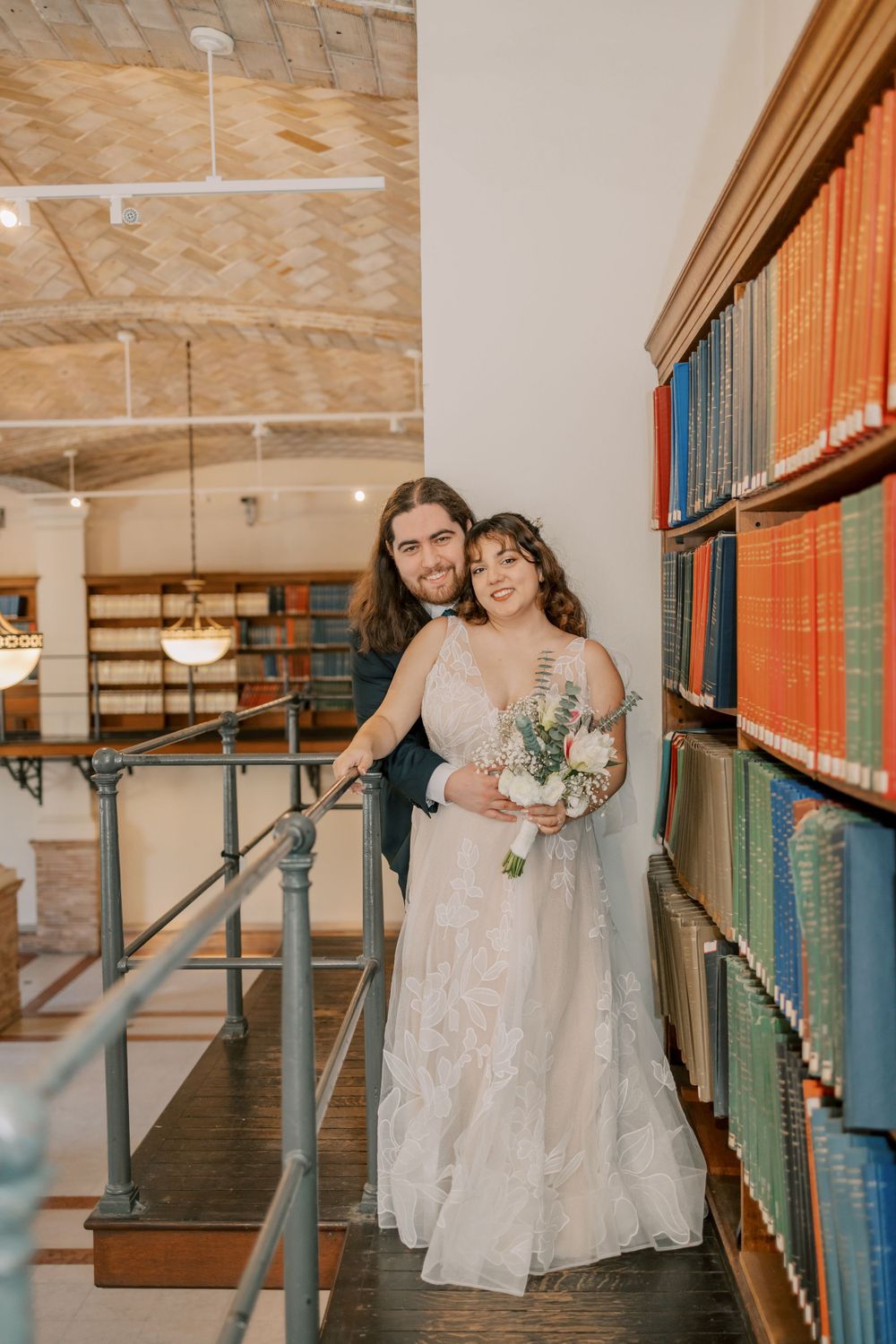 A cozy wedding portrait in a library featuring a couple embracing among rows of colorful books.
