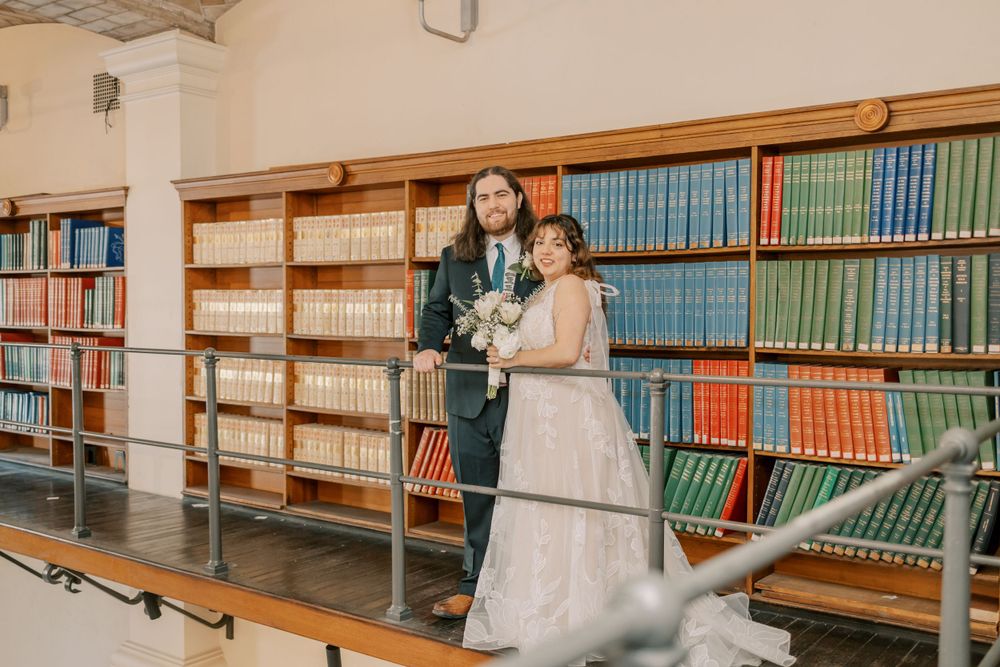 A wedding portrait taken in a historic library with wooden bookshelves and vintage books.