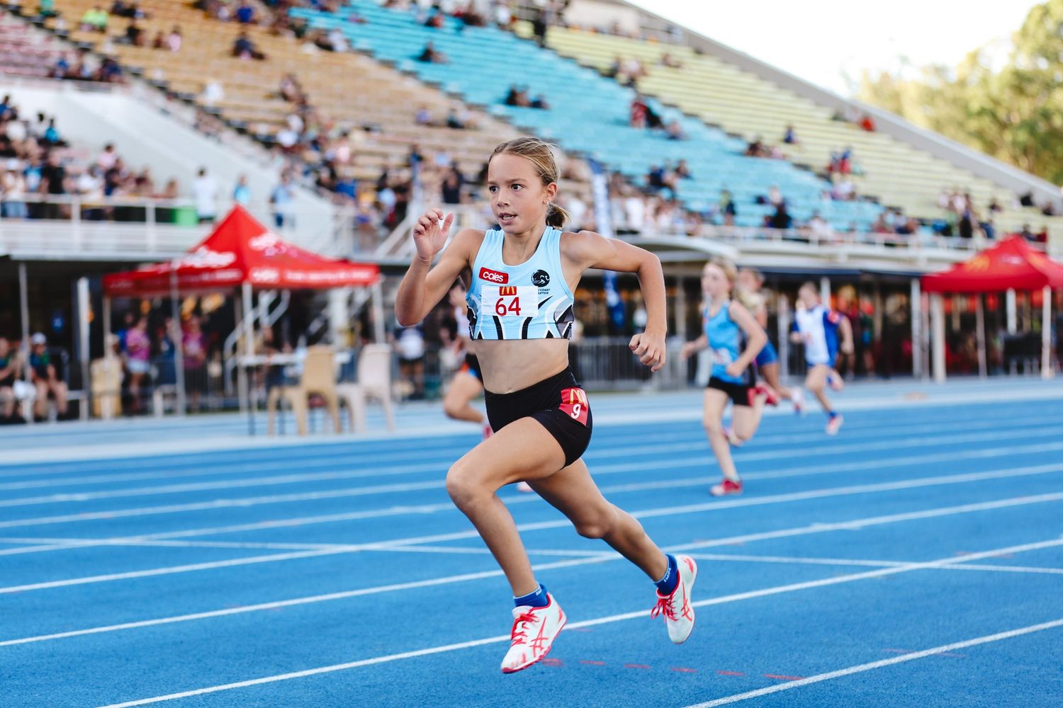 Runner competes on blue track during competition with a powerful stride in athletics event.