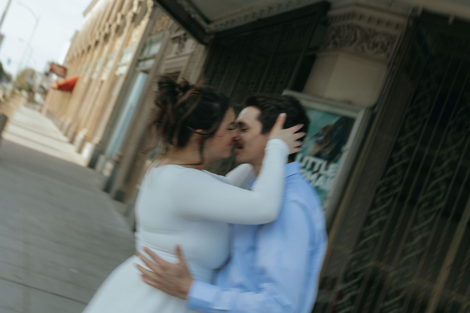 A blurry/unfocused photo of a couple kissing in front of a theater.