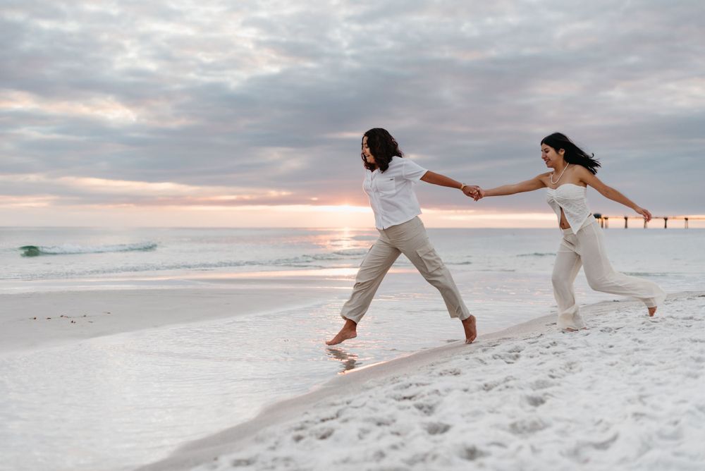 Playful couple running and splashing in the surf at sunset on a white sandy beach.