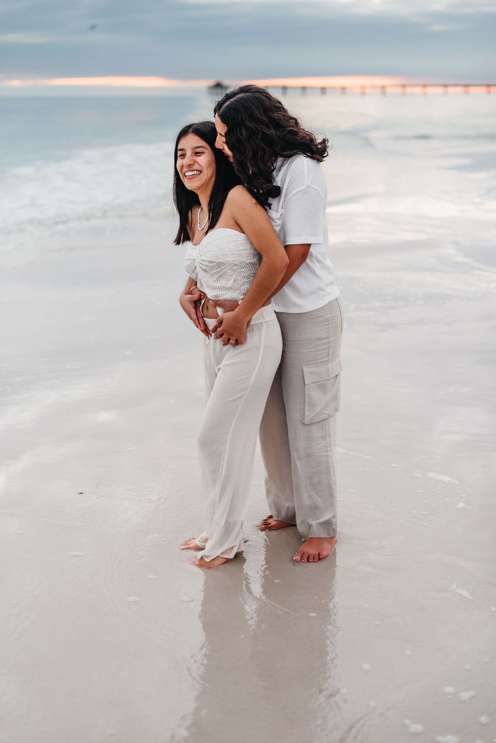 Intimate beach photoshoot with couple wearing white and beige walking in the sand.