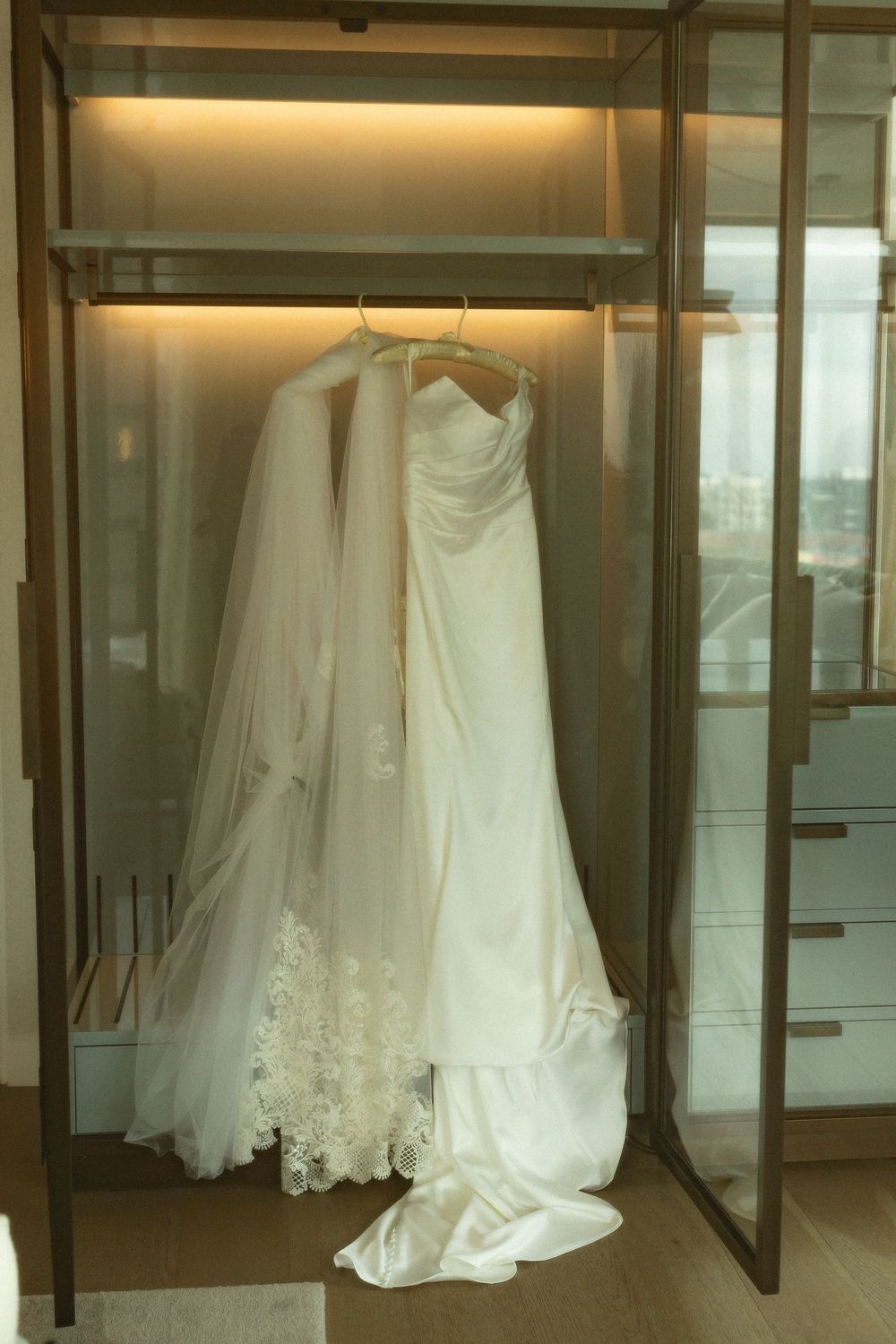 Wedding dresses displayed in glass cases at a bridal boutique, showcasing elegant white gowns with lace details.