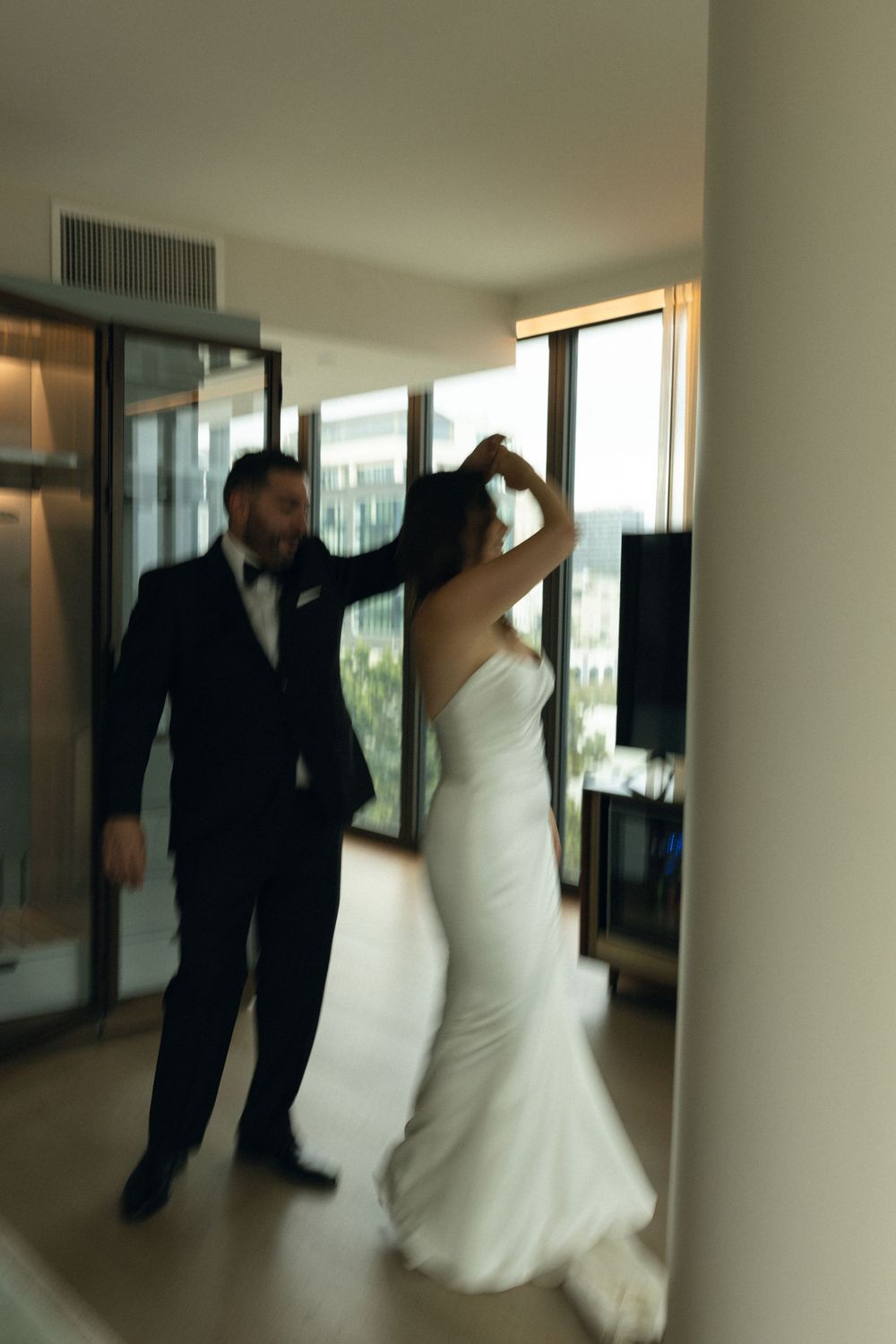 A couple dances together in an indoor setting, with the bride wearing a flowing white wedding dress.