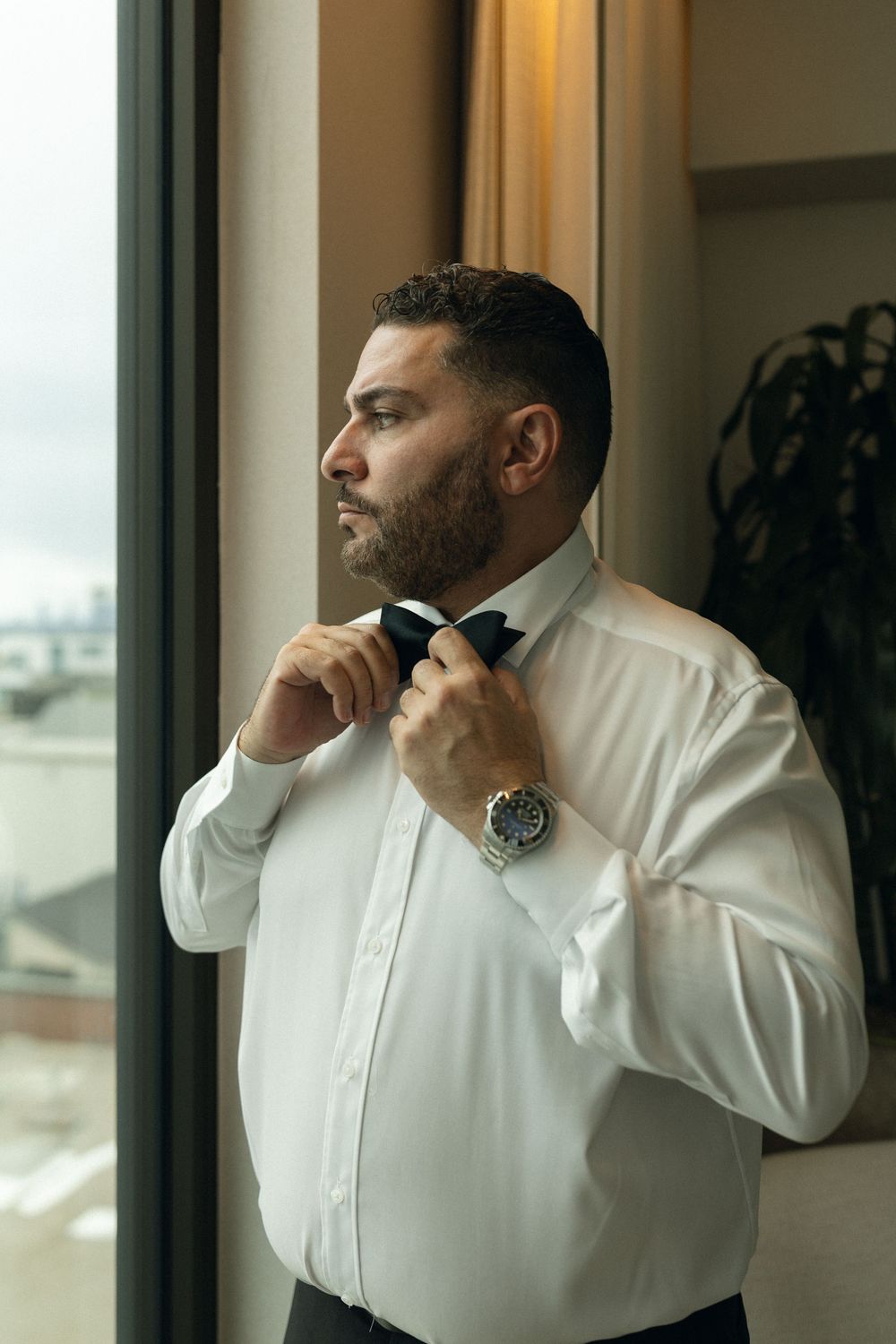 Professional in white shirt adjusts collar while looking out window in four sequential photos.